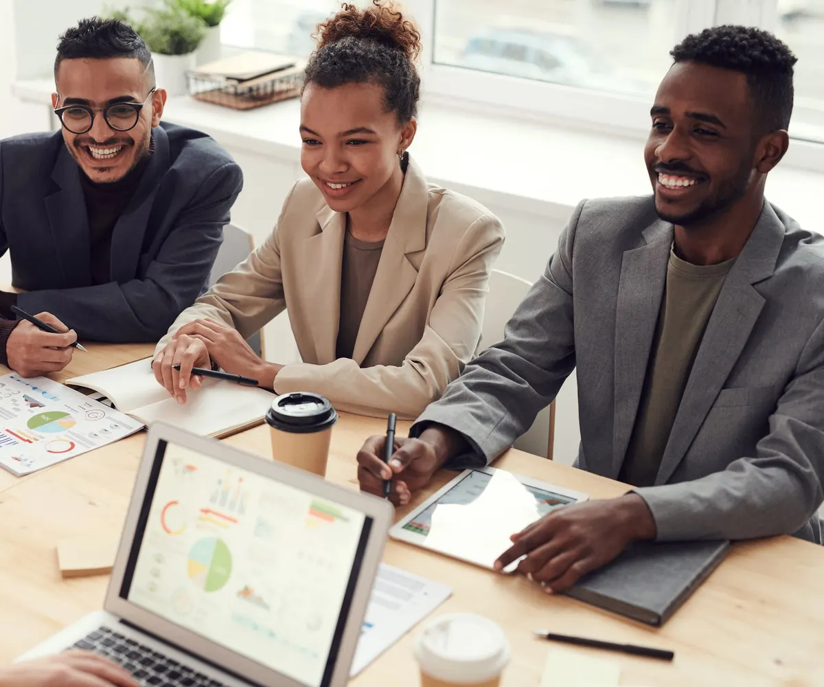 Equipe reunida em volta de um notebook, sorrindo durante uma conversa de trabalho